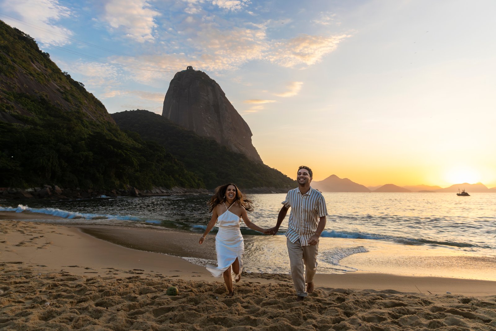 Couple running on the beach at sunrise with Sugarloaf Mountain
